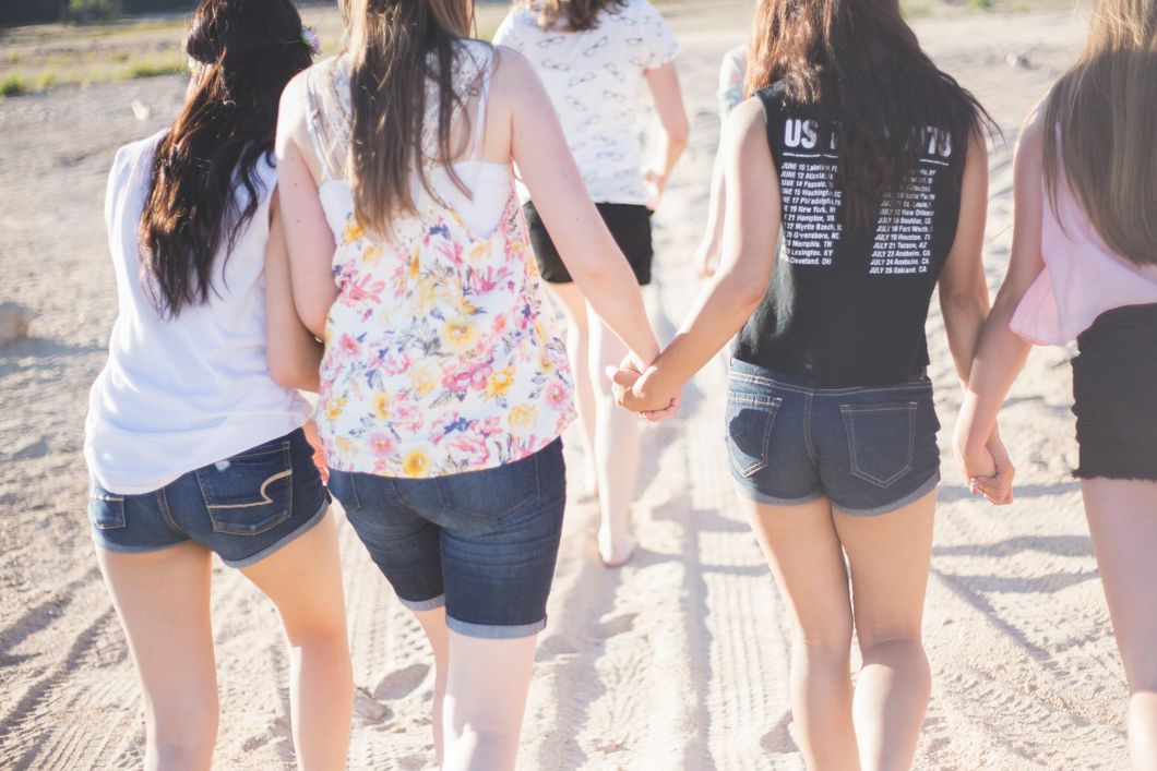 4 women holding hands and walking