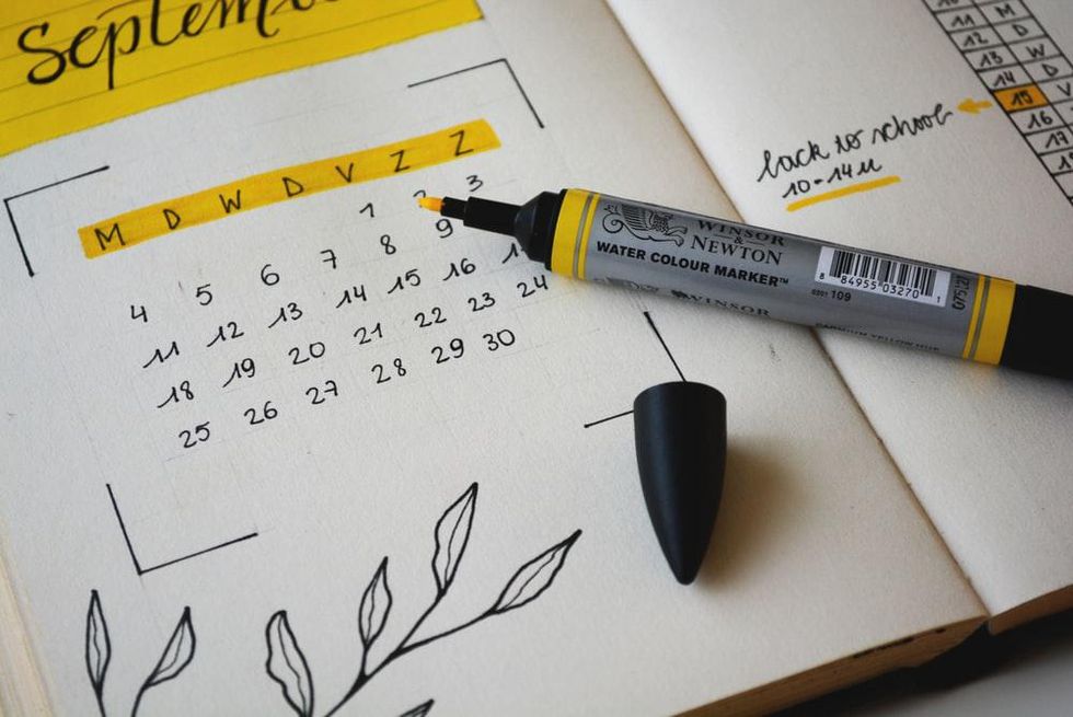 A black, white, and yellow calendar, with floral decals in the corner and yellow highlighter laying across the page.
