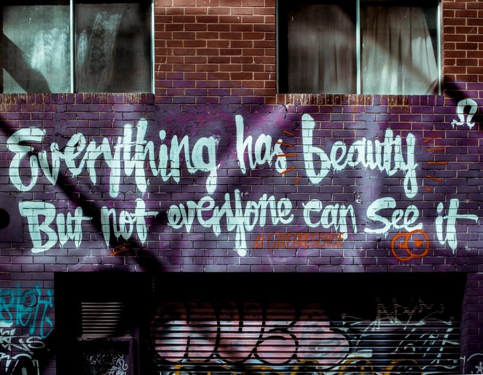 A brick wall with graffiti that says "everything has beauty but not everyone can see it".