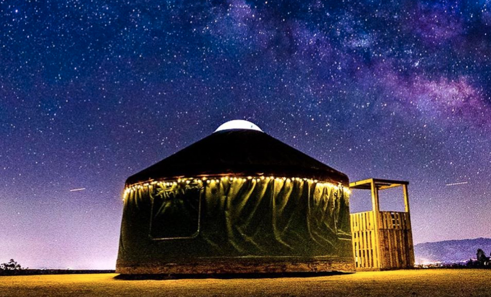 A circular yurt-style home at night with a star-studded night in the background