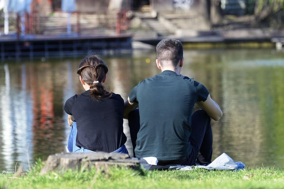 A couple sits on the shore of the river