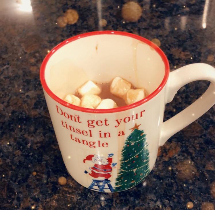 A festive holiday mug with hot cocoa and marshmallows inside