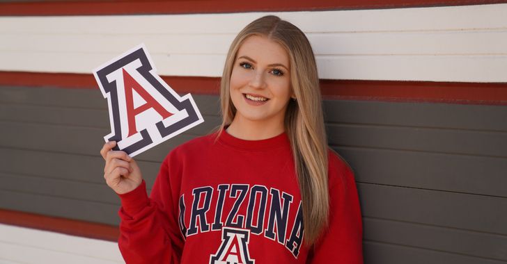 a girl in red arizona sweatshirt holding up a sign