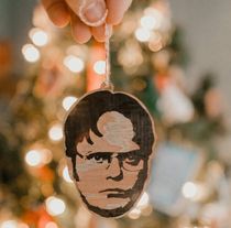 a hand holding a wooden ornament with a picture of a man on it