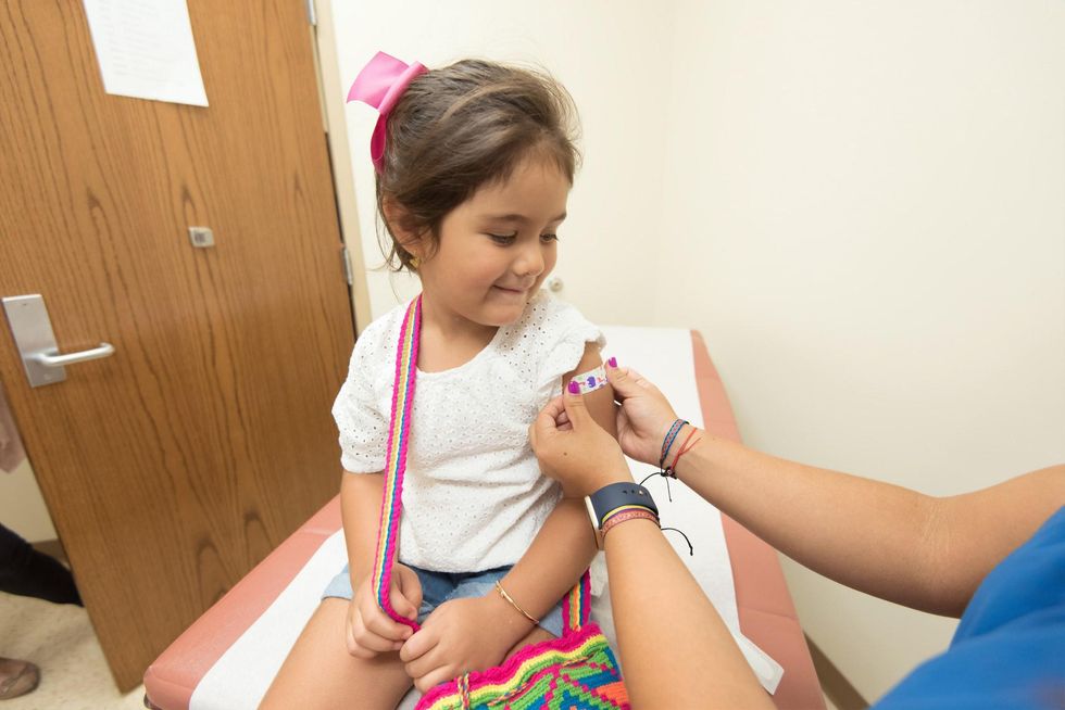 a health care provider was placing a bandage on the injection site of a child