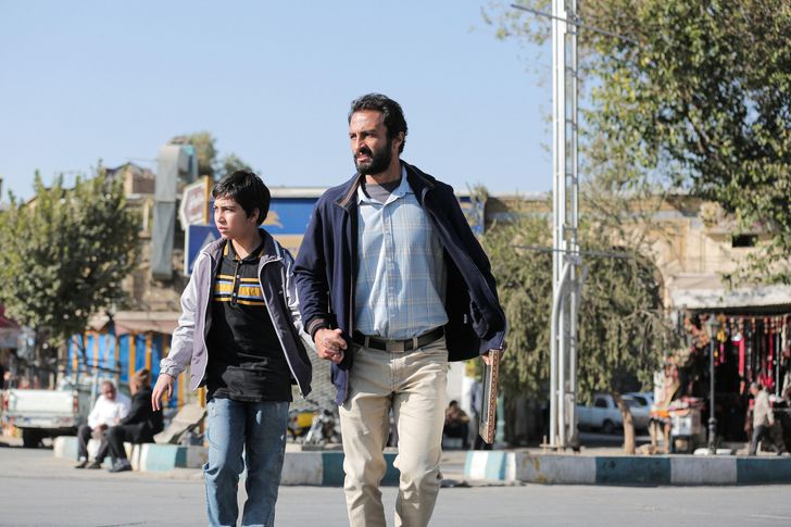 A movie still photo of Amir Jadidi (right) as Rahim and his young movie son in Amazon Studios' "A Hero."