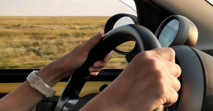 a persons arms holding a steering wheel whilst driving