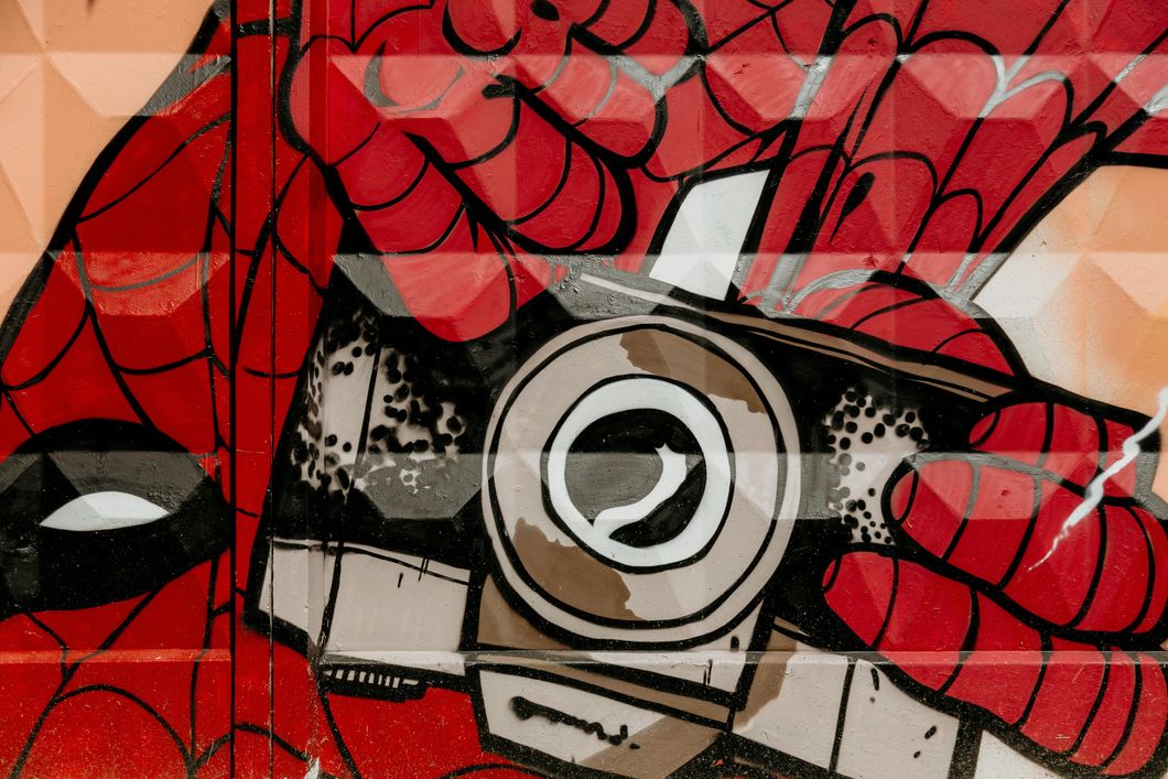 A picture of a comic style painting of Spider-Man, upside down and holding a camera.