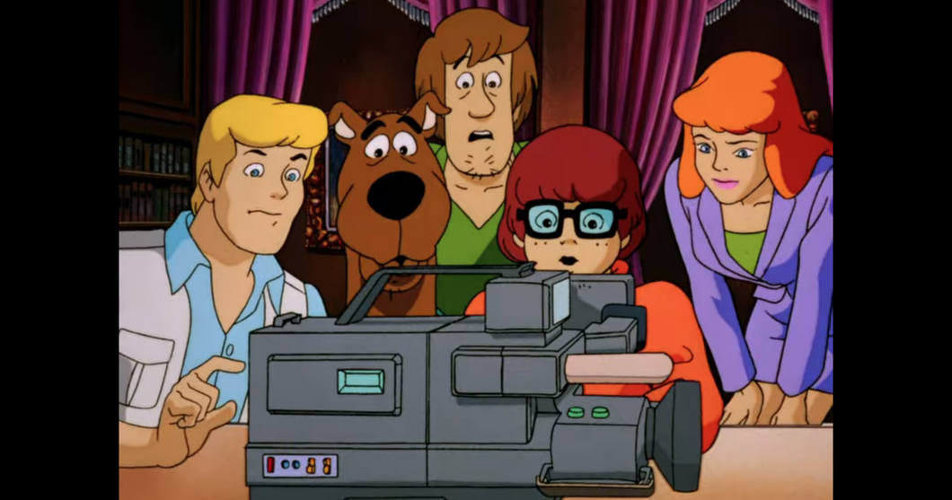 A screenshot from "Scooby-Doo on Zombie Island" with (from left) Fred, Scooby-Doo, Shaggy, Velma and Daphne looking at footage from Fred's camera.