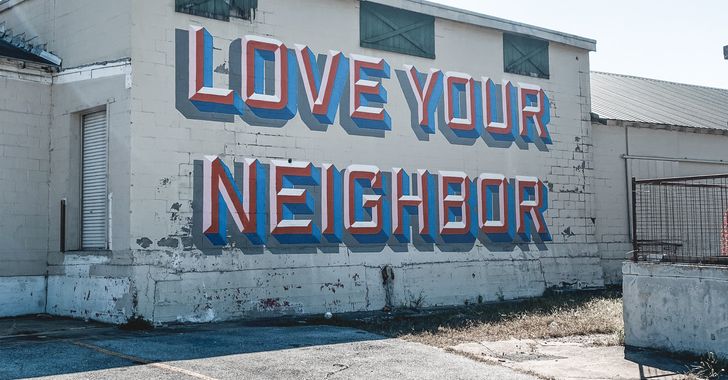a wall with a sign that says love your neighbor