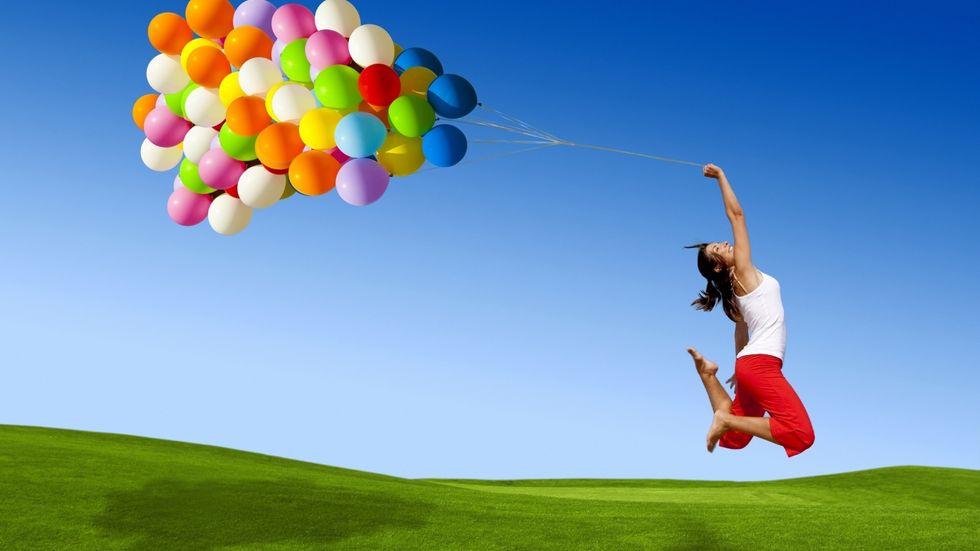 a woman jumping with confidence with balloons