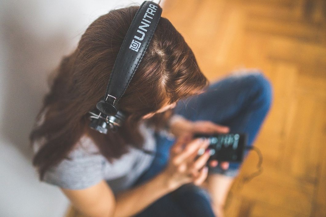 A woman listening to music on her phone with headphones.