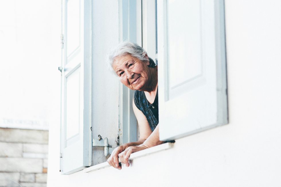 A women leaning on a windowsill, looking outside.