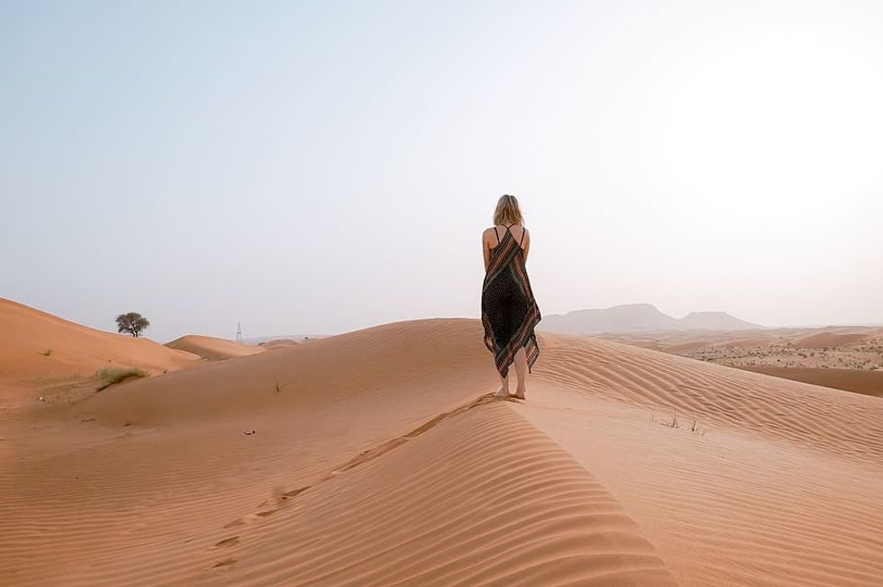 A young girl walking alone in the desert. 