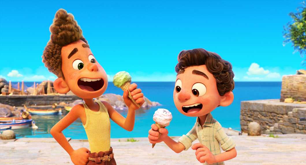 Alberto (left) and Luca (right) stare in awe at their gelatos in their hands. In their background, they are standing alongside a dock in a seaside town off the Italian Riviera.