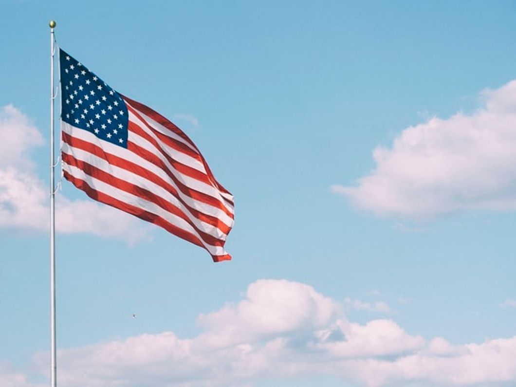 American flag beneath a cloudy blue sky.