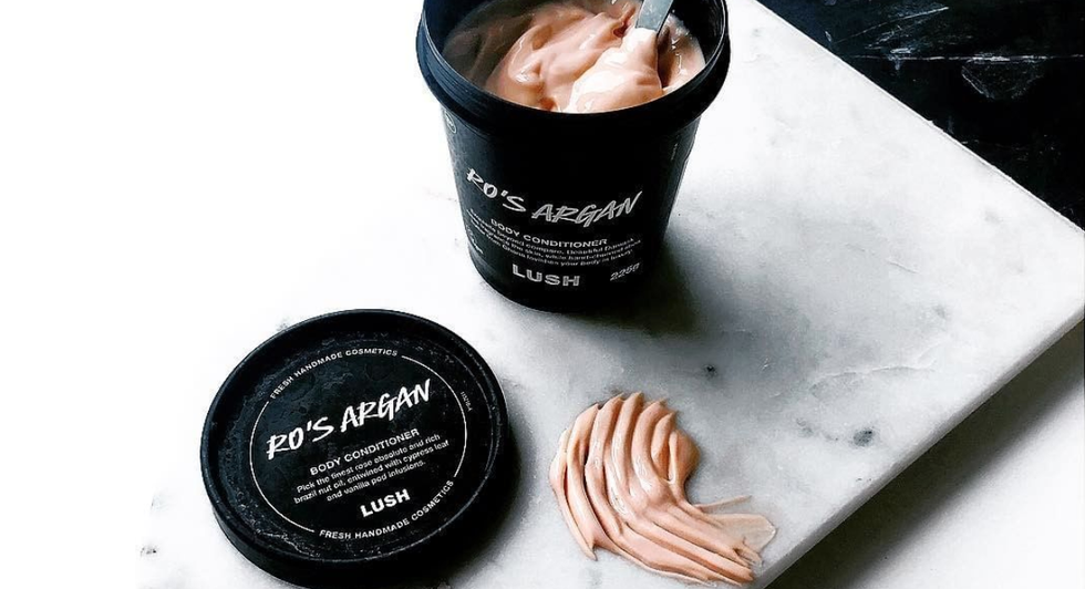 an open, black tub that with light pink cream in it on top of a marble board