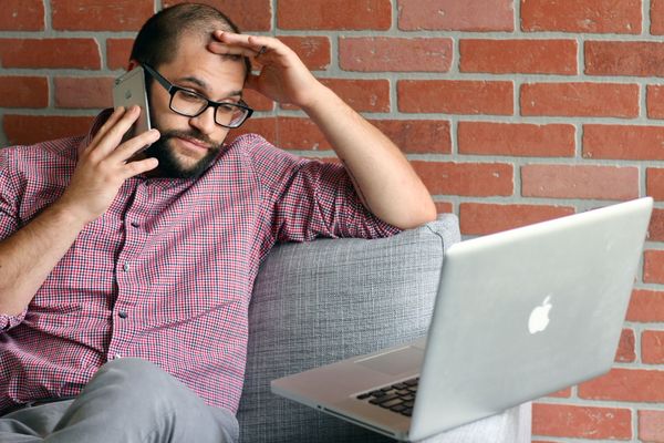 annoyed man on phone looks at laptop