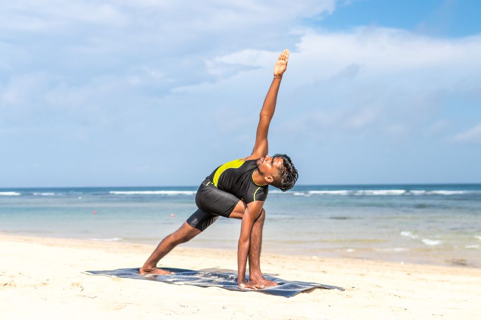 attractive fit young man doing yoga on the beach