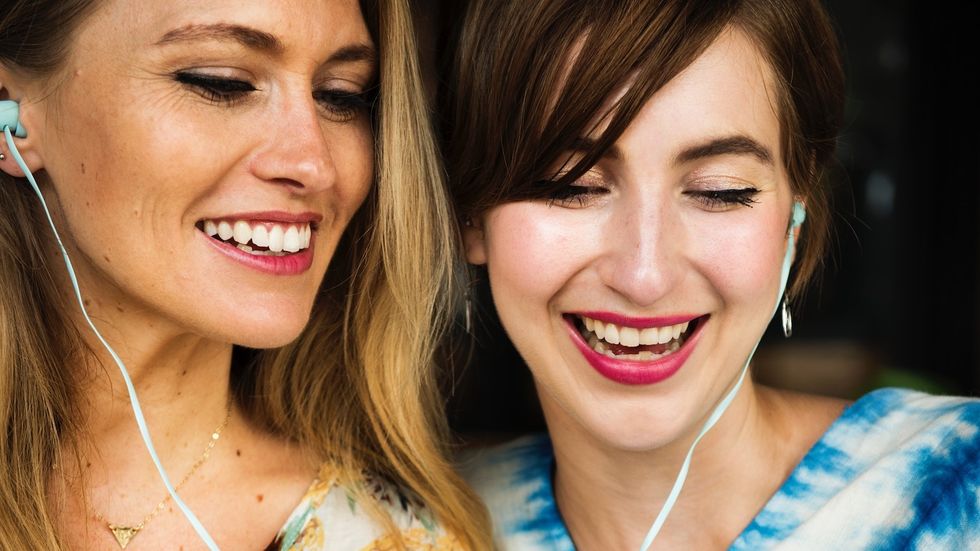 best girl friends listening to music sharing headphones