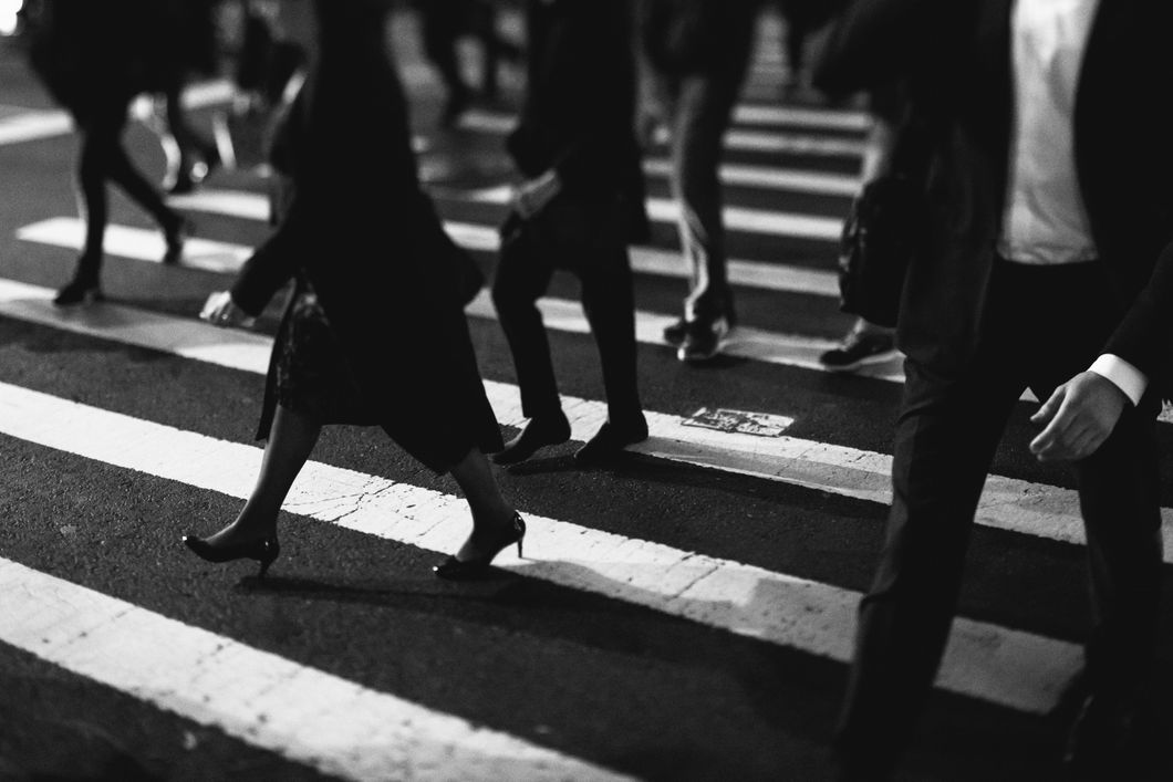 Black and white picture of people walking through a cross walk