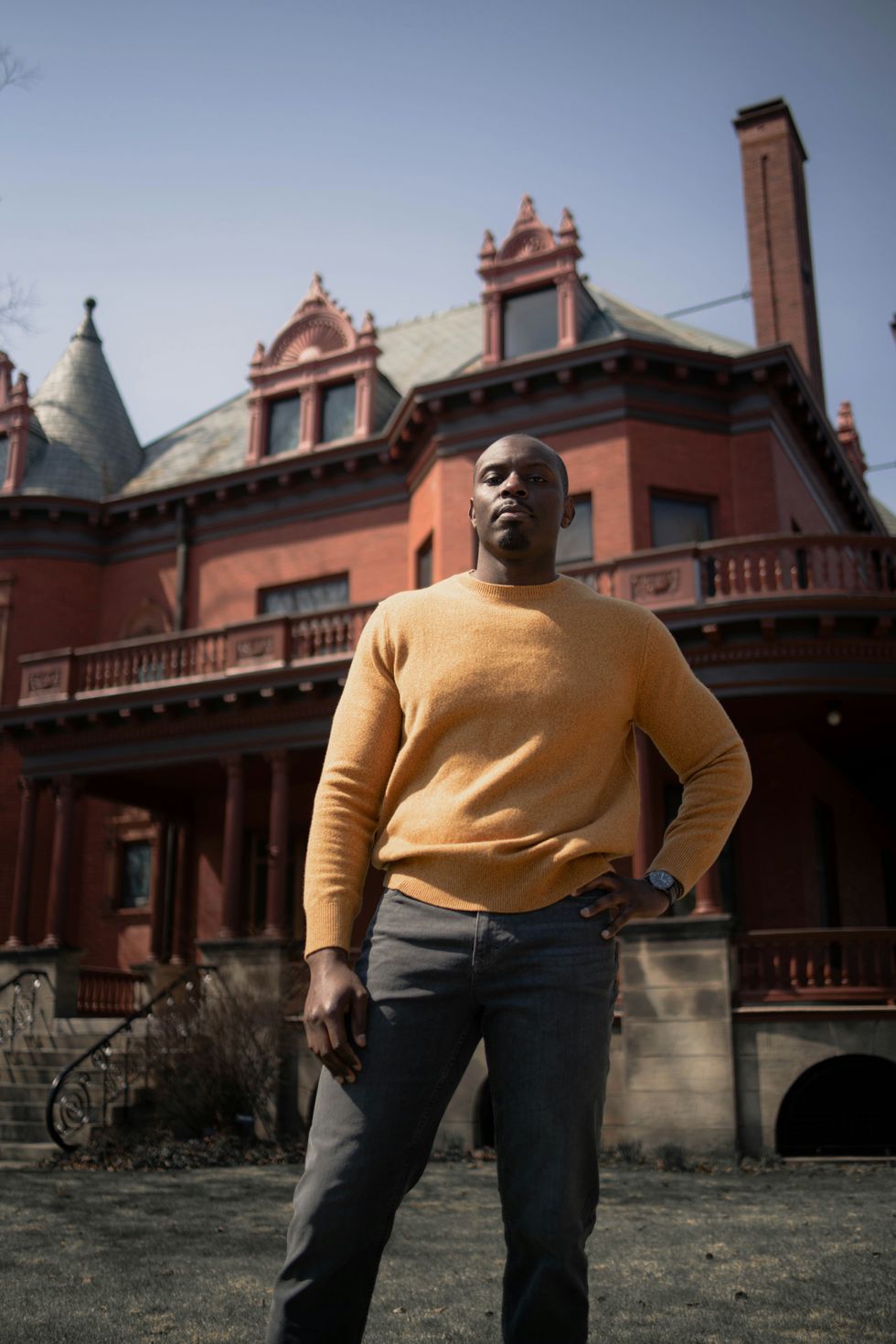black man in yellow turtleneck sweater standing in a confident stance
