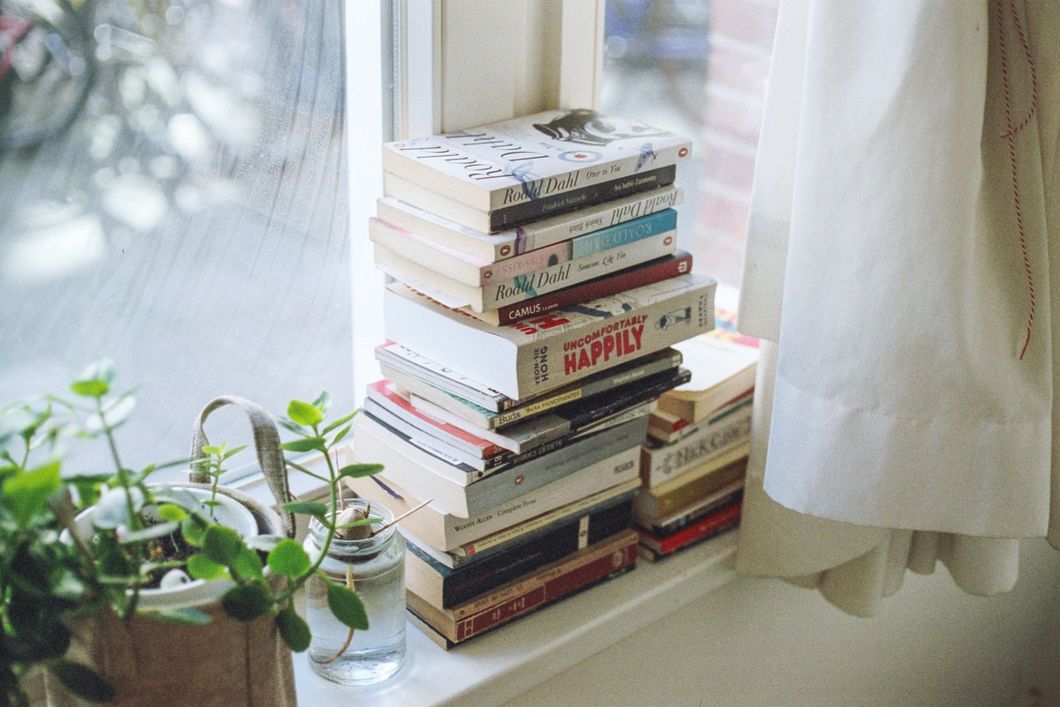 Books stacked up next to a window