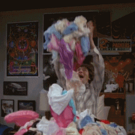 Boy on a bed throwing his dirty laundry in the air 