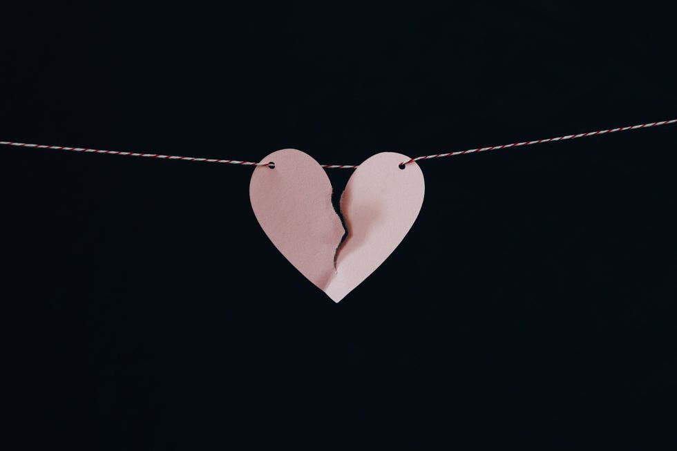 broken paper heart held up on a string