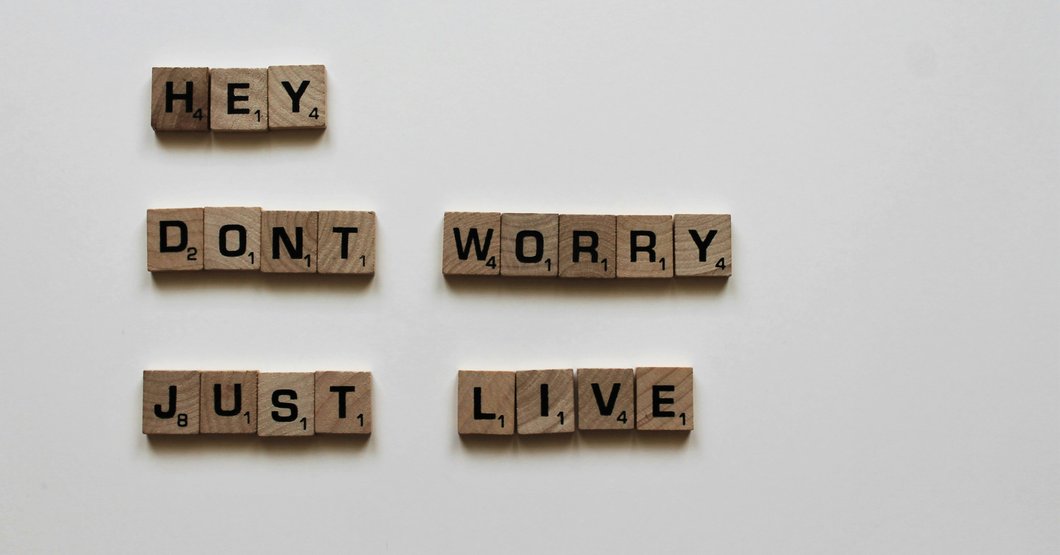 Brown wooden game tiles saying hey don't worry just live
