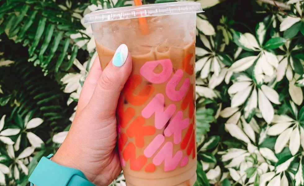 close-up of an iced coffee in a dunkin cup with some greenery behind it