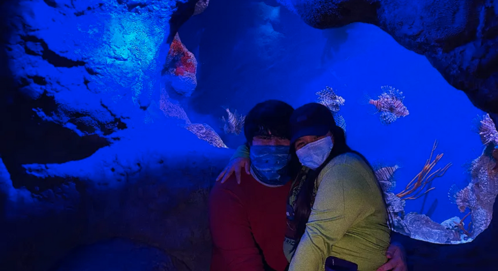 couple hugging in front of large, blue fish tank