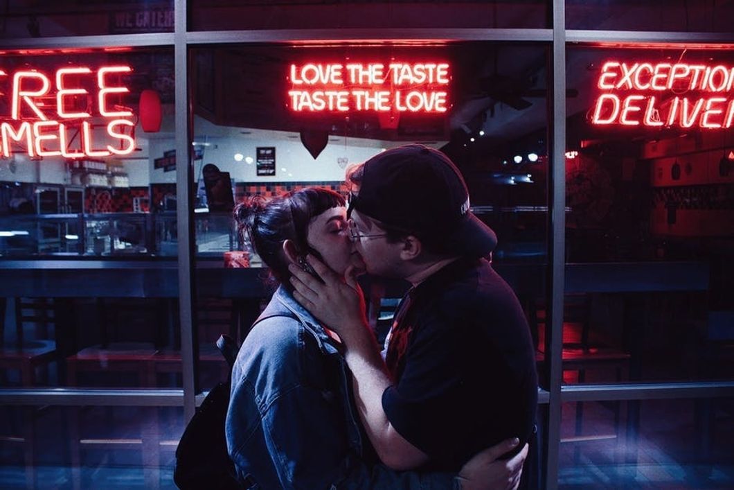 couple kissing in front of restaurant with neon signs