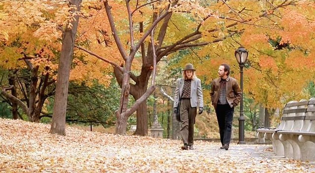 Couple walking through trees in the autumn