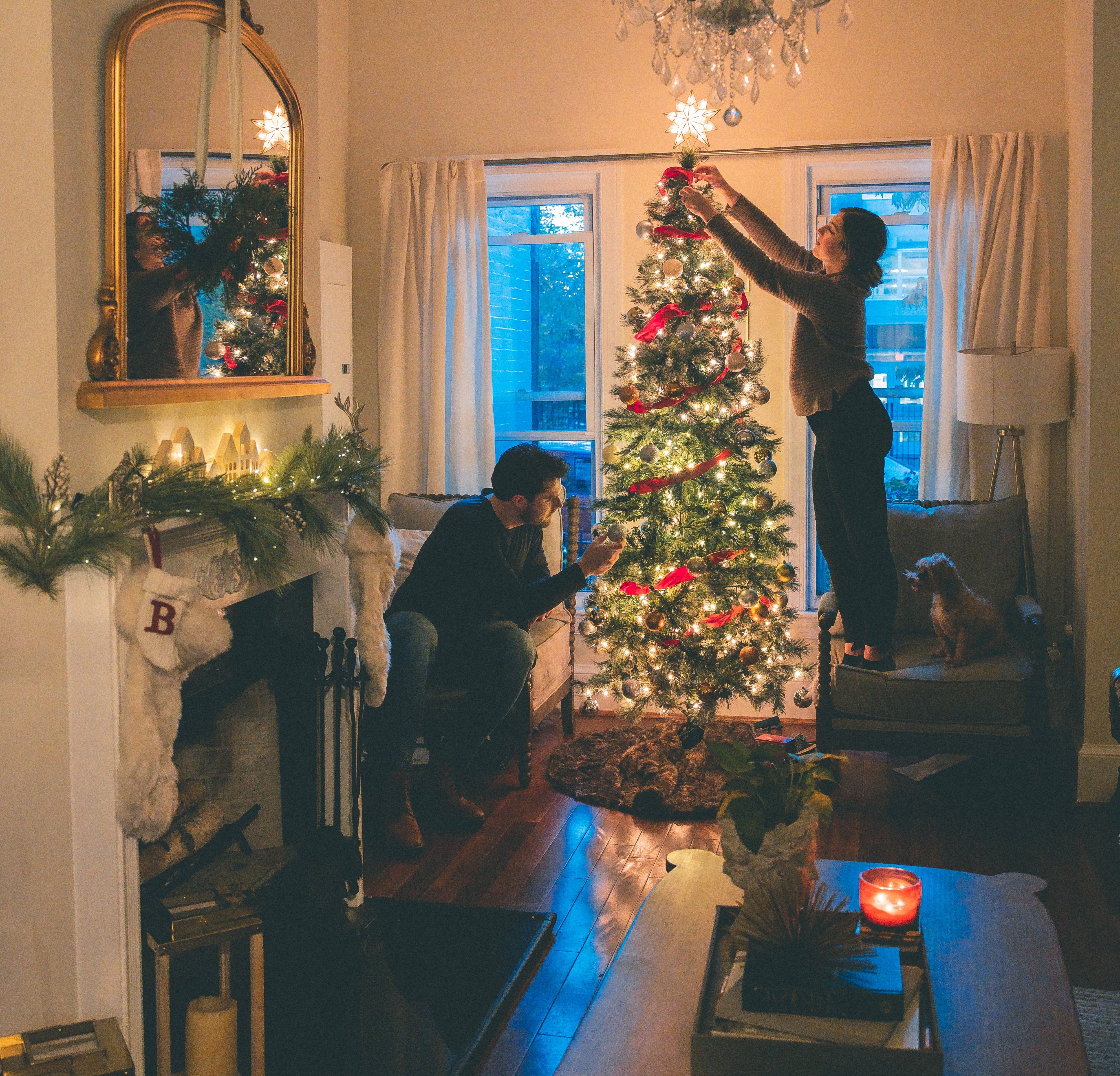 Couple with their dog decorating the Christmas tree. 