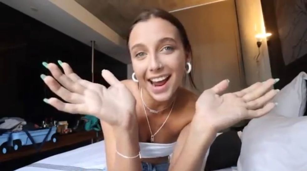Emma Chamberlain with her hands up and outward.