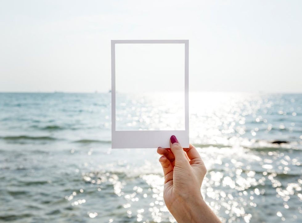 Empty white frame held up against the background of a sunlit sea.