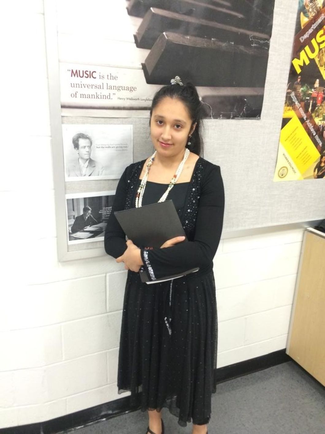 Erikka, wearing all black, holding sheet music