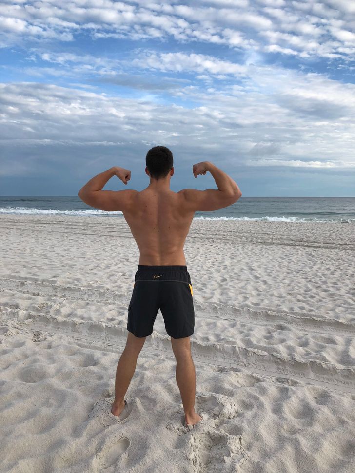 fit man flexing muscles on beach