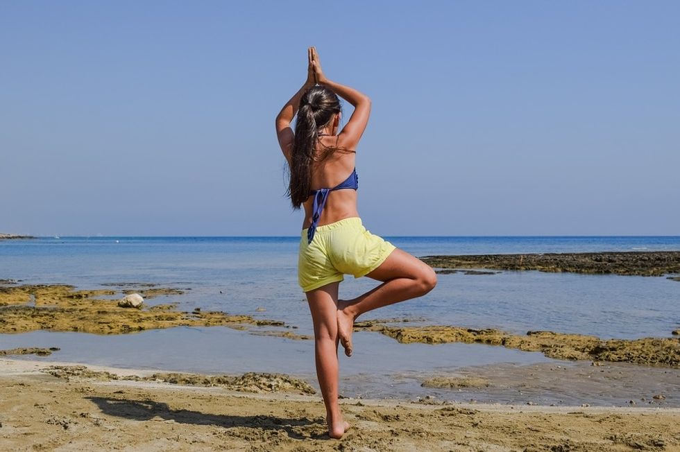 fit woman doing yoga on beach