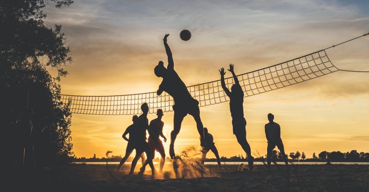 friends playing volleyball at sunset