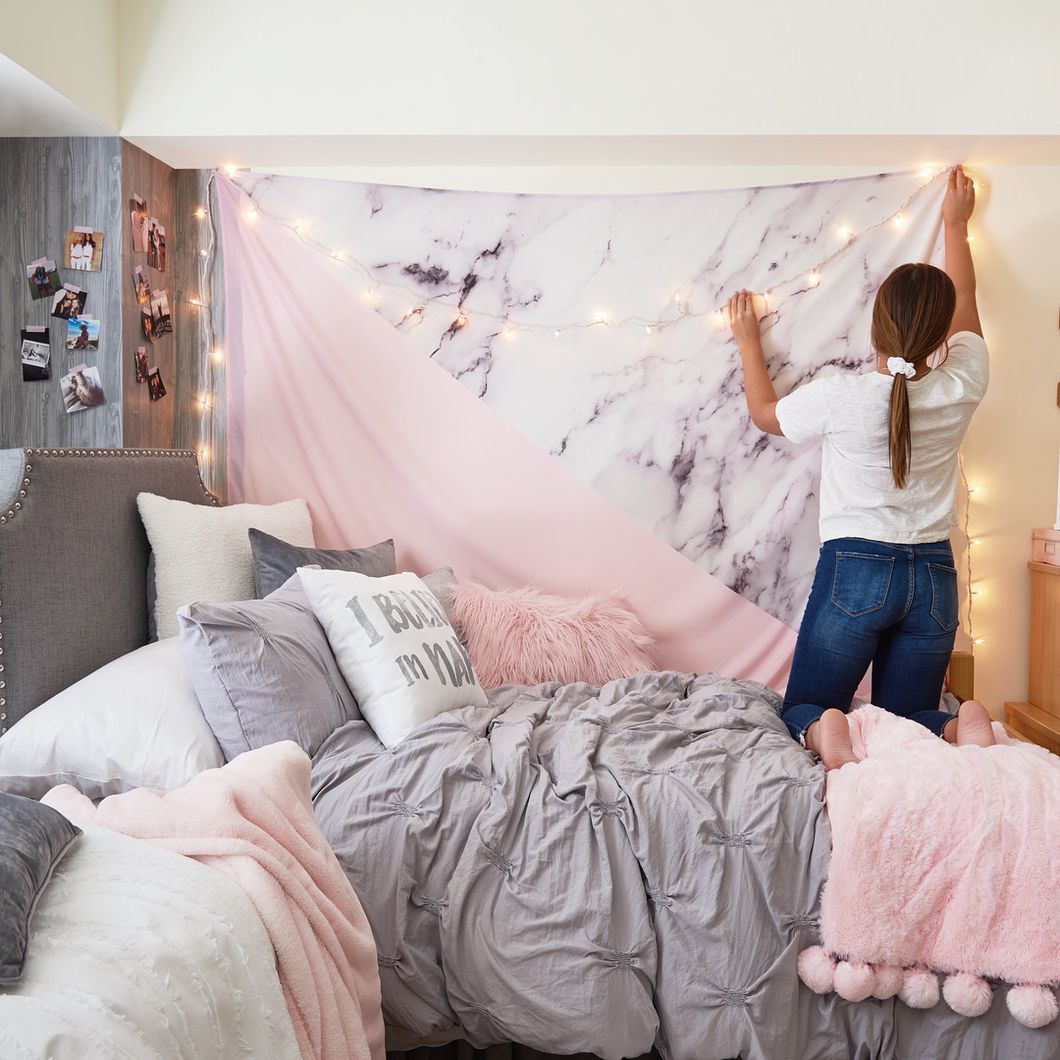 girl decorating wall of dorm room with lights