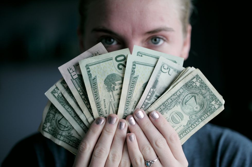 Girl holding money in front of her face