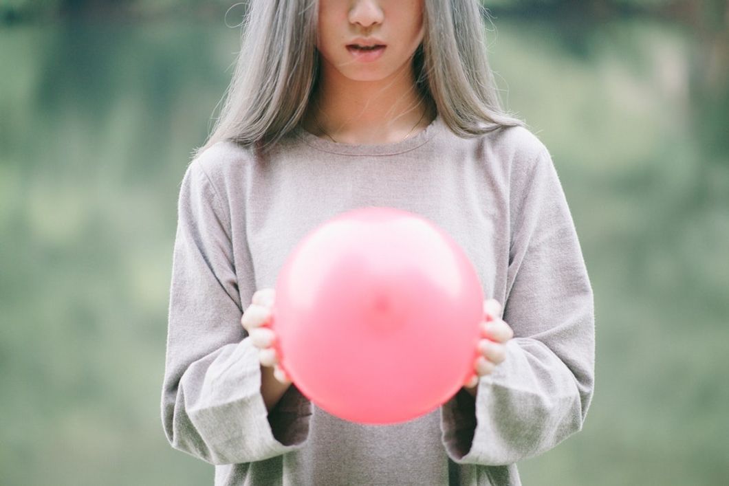 girl holding pink balloon in her hands