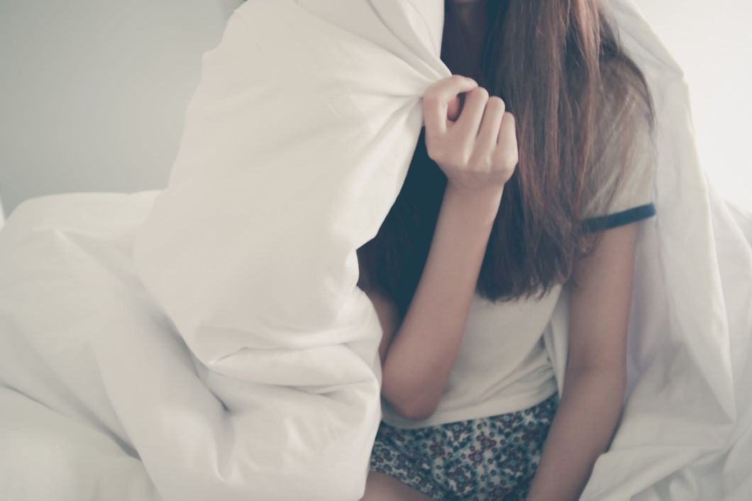 girl in bed holding blanket over her shoulder