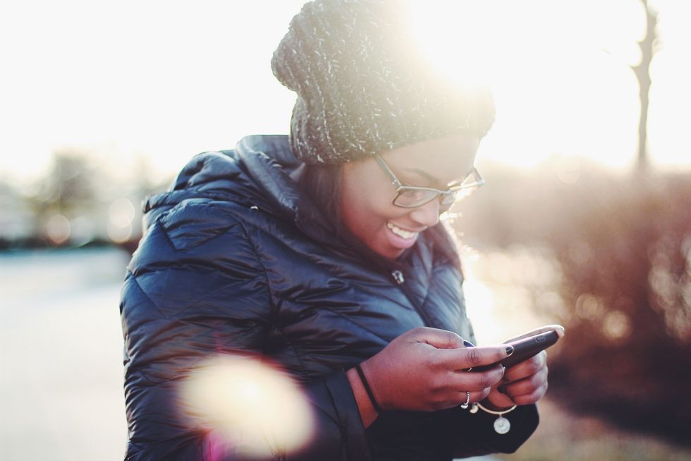Girl in coat and beanie on her phone, smiling