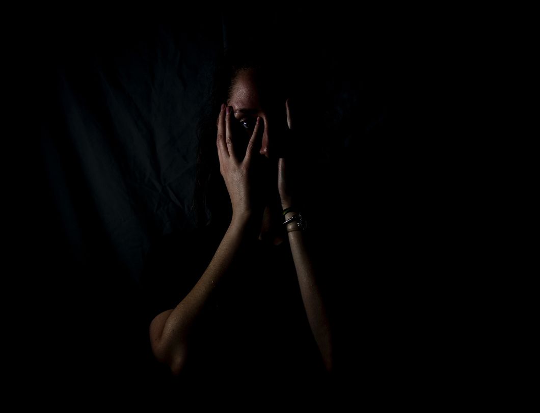 Girl in the dark with her hands over her face