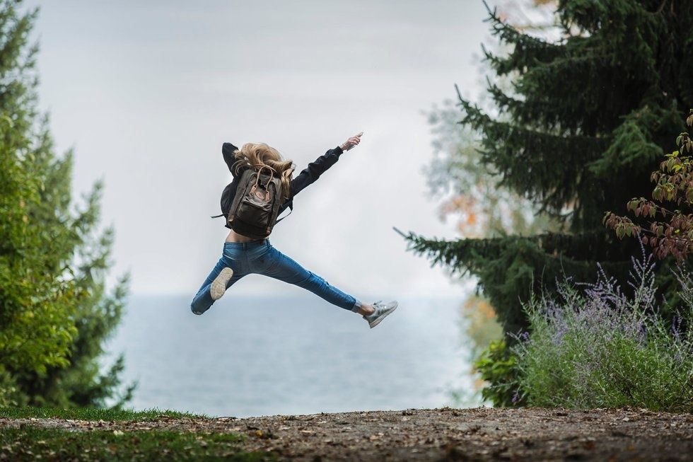 Girl jumping into the air with back turned in a nature setting