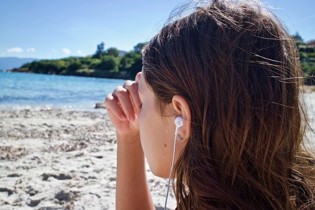 girl listening to music by the water