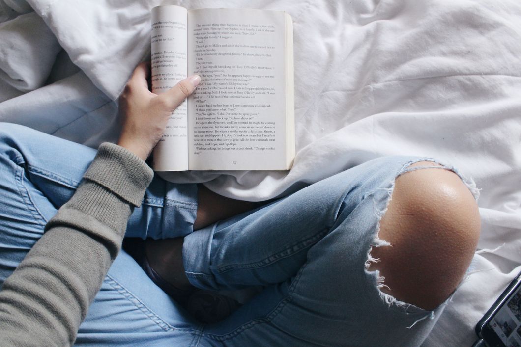 Girl reading a book on her bed
